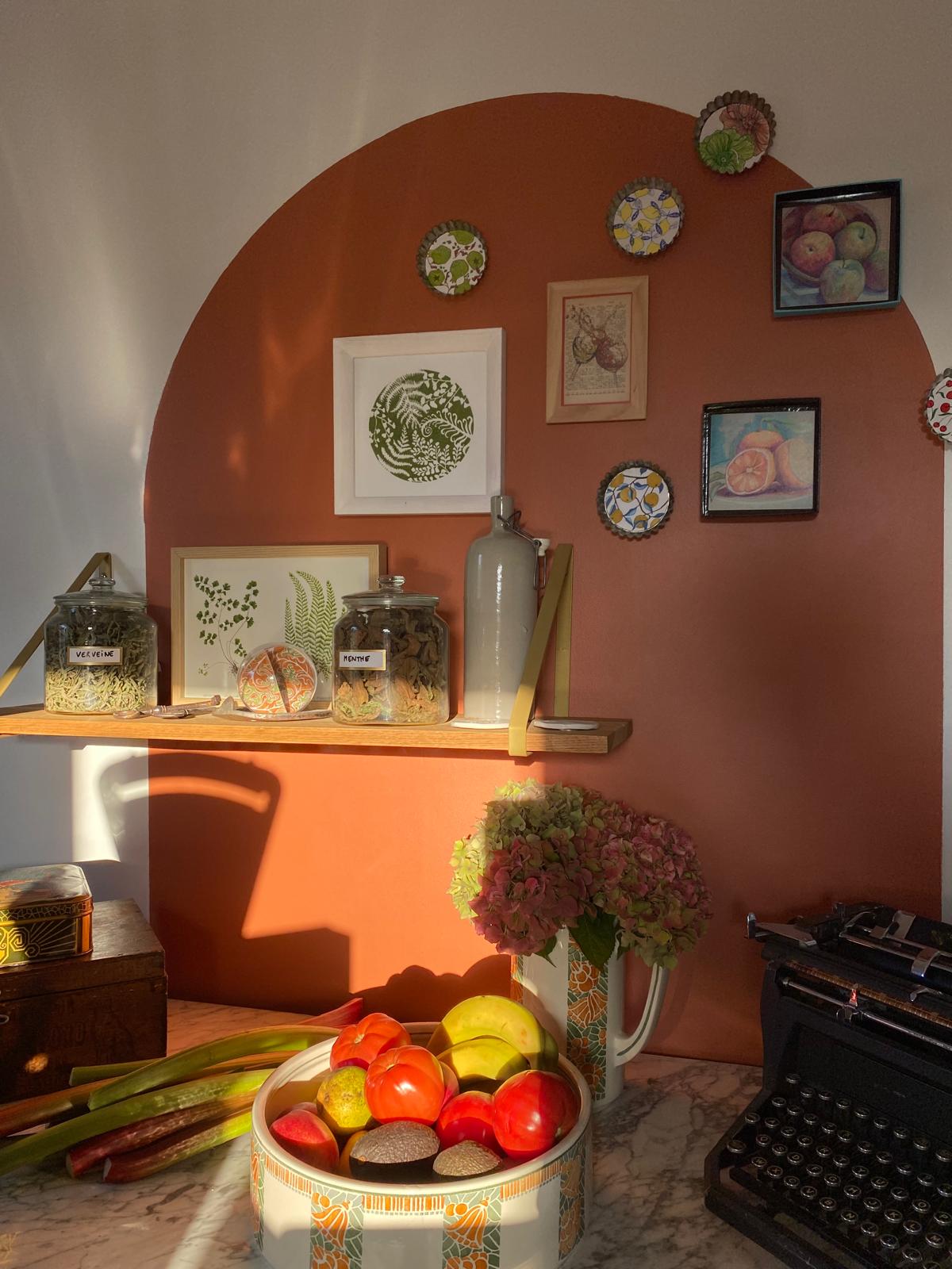 Des éléments déco sur une arche en peinture terracotta dans une cuisine