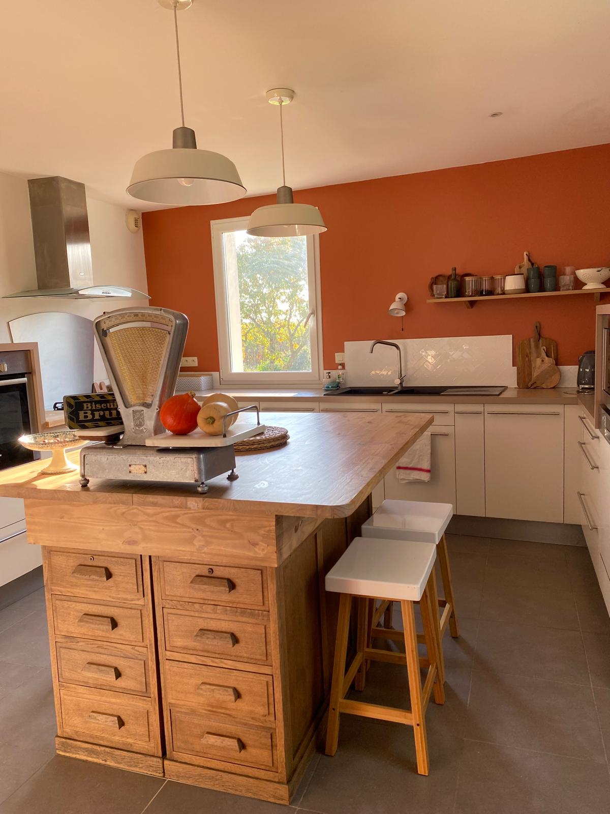 Une cuisine terracotta chaleureuse avec un îlot central en bois fabriqué à partir de meubles chinés