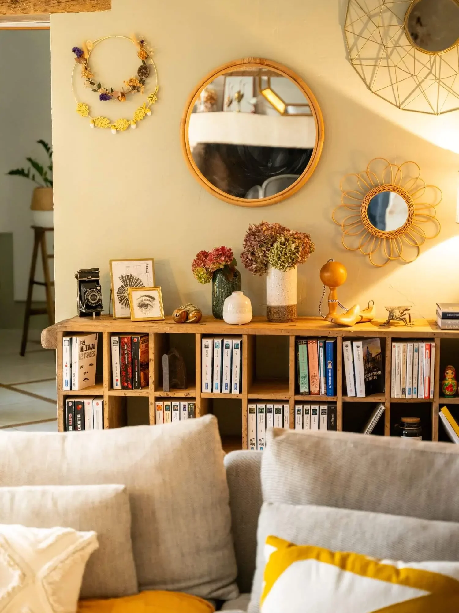 Bibliothèque créée à partir d’un meuble ancien, mur vert et accumulation de miroirs dans un salon.