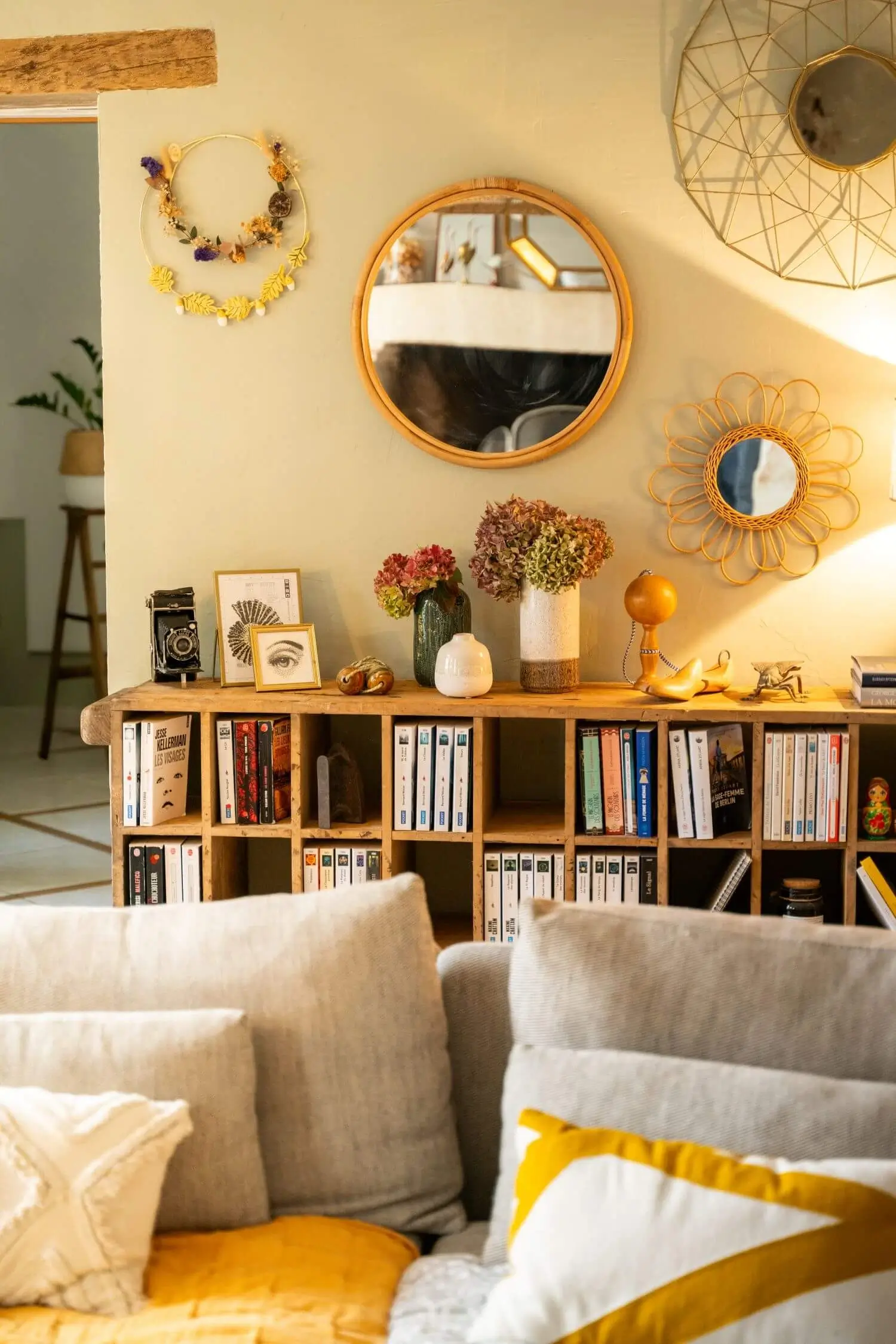 Bibliothèque créée à partir d’un meuble ancien, mur vert et accumulation de miroirs dans un salon.