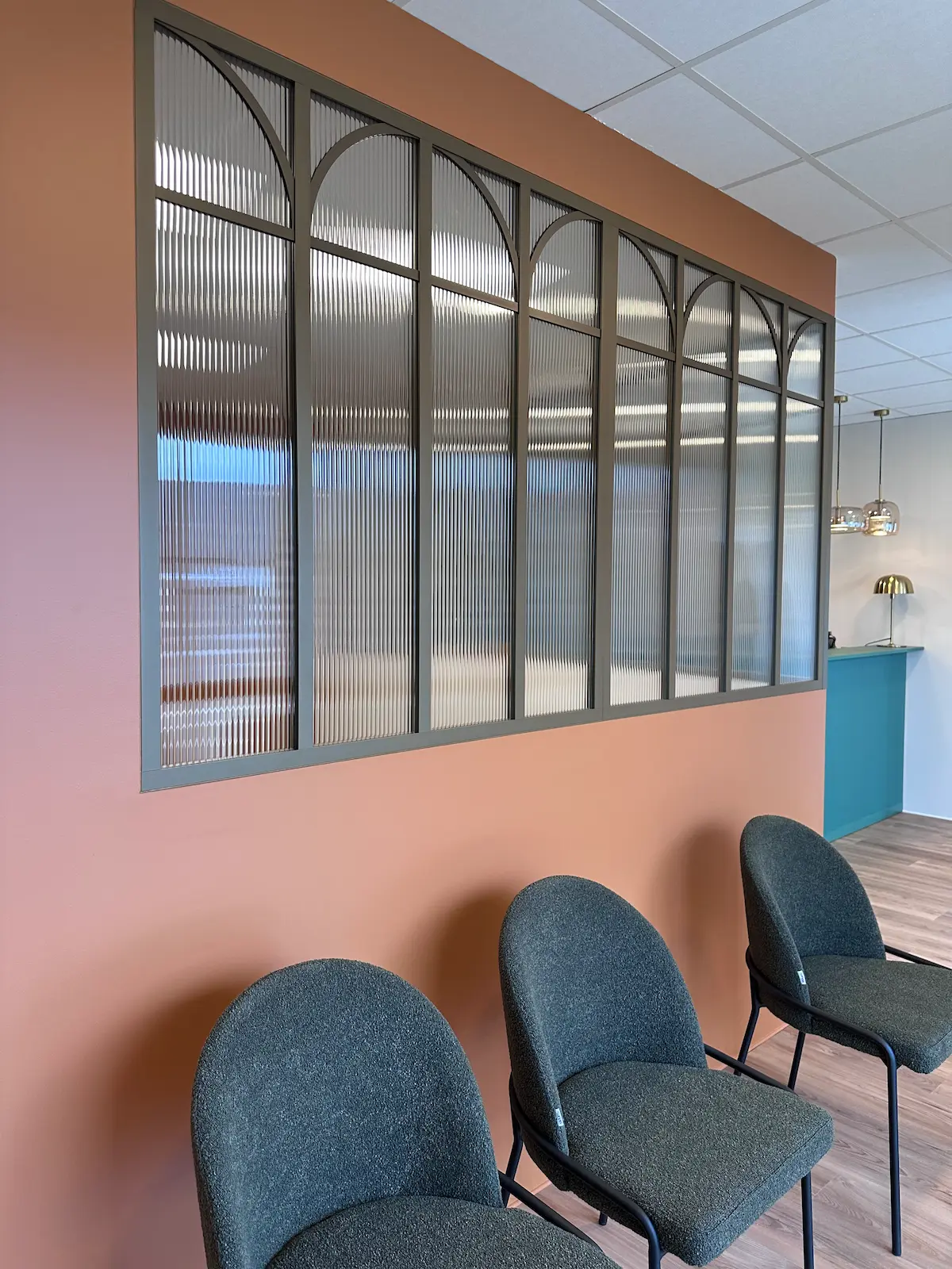 Salle d’attente d’étude notariale décorée dans les tons vert sauge et orange poudré pour apaiser les visiteurs