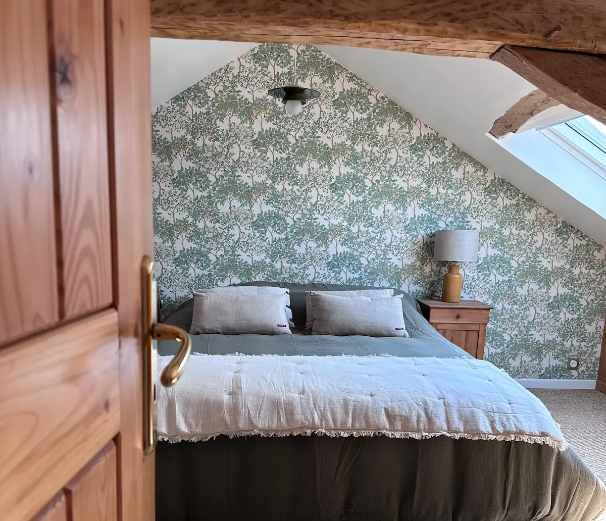 Chambre sous pente décorée dans un esprit maison d’hôtes avec poutres apparentes