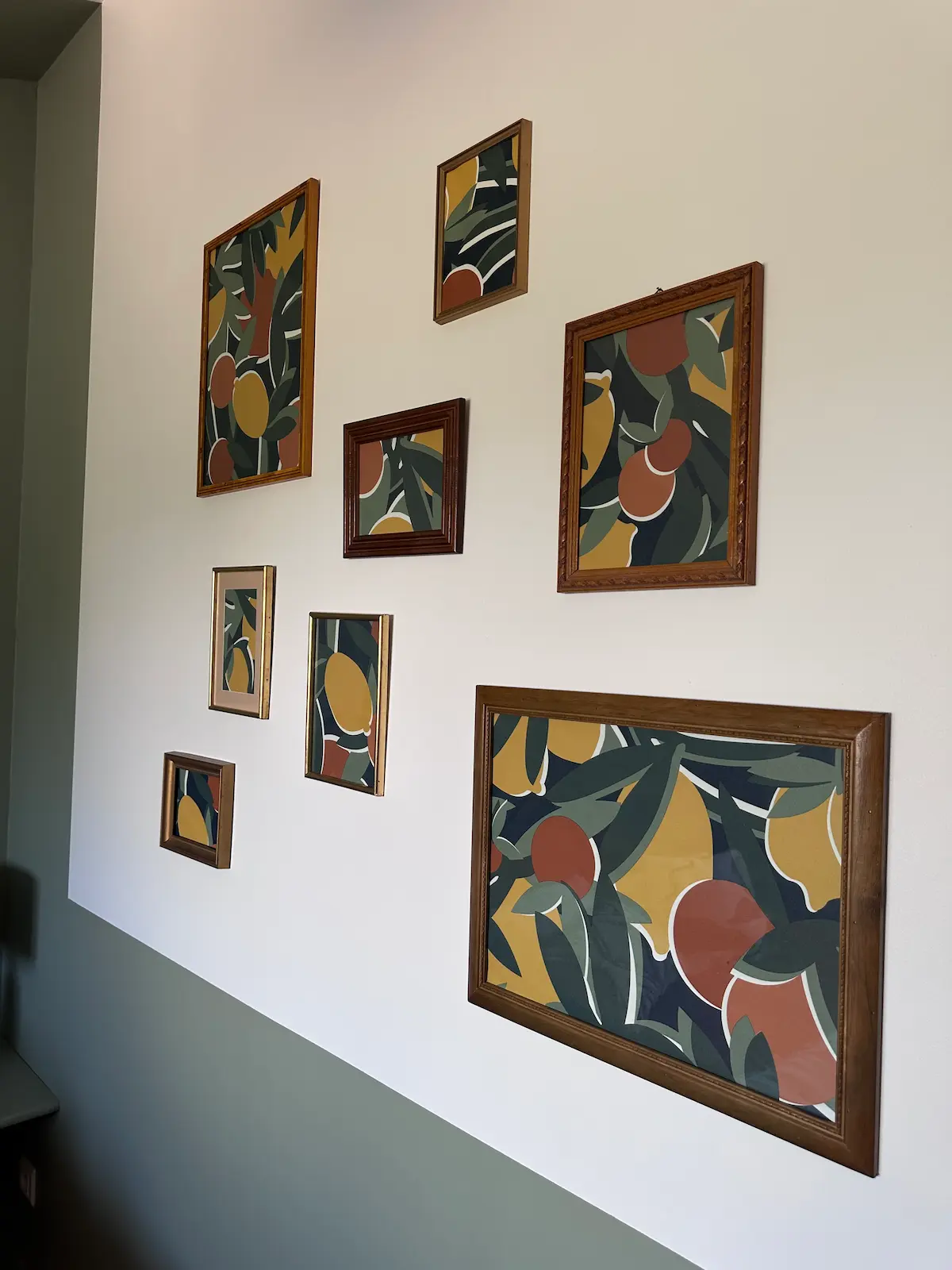 Un papier peint aux motifs colorés de citrons encadrés dans des cadres sur le mur d’une chambre